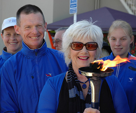 Nita Knight holds the World Harmony Run torch surrounded by members of the Harmony Run team. title=